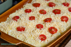 Oranje bruine ovenschaal met daarin de nog ongebakken ovenschotel met spitskool, prei en komijn gemaakt door deedylicious.