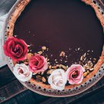 Italiaanse chocoladetaart versierd met bloemen en pistachenoten