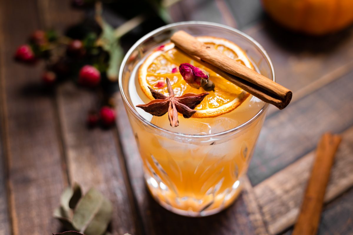 Glas met kruidige cocktail met kaneelstokje bovenop