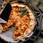 Hartige galette met pompoen en spitskool met een blok Parmezaanse kaas en Micoplane ernaast.