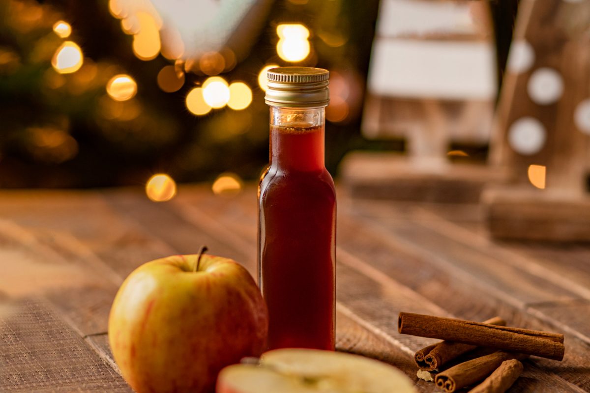 Flesje Apple Crisp koffiesiroop met daarnaast stukjes appel en stokjes kaneel